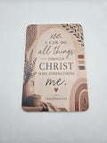 A rectangular printed card or plaque with rounded corners, shown on a plain light background. The design features the words 'I CAN DO all things THROUGH CHRIST WHO STRENGTHENS me' and 'PHILIPPIANS 4:13,' with decorative wheat illustrations and a rustic brown-and-beige illustration at the bottom.